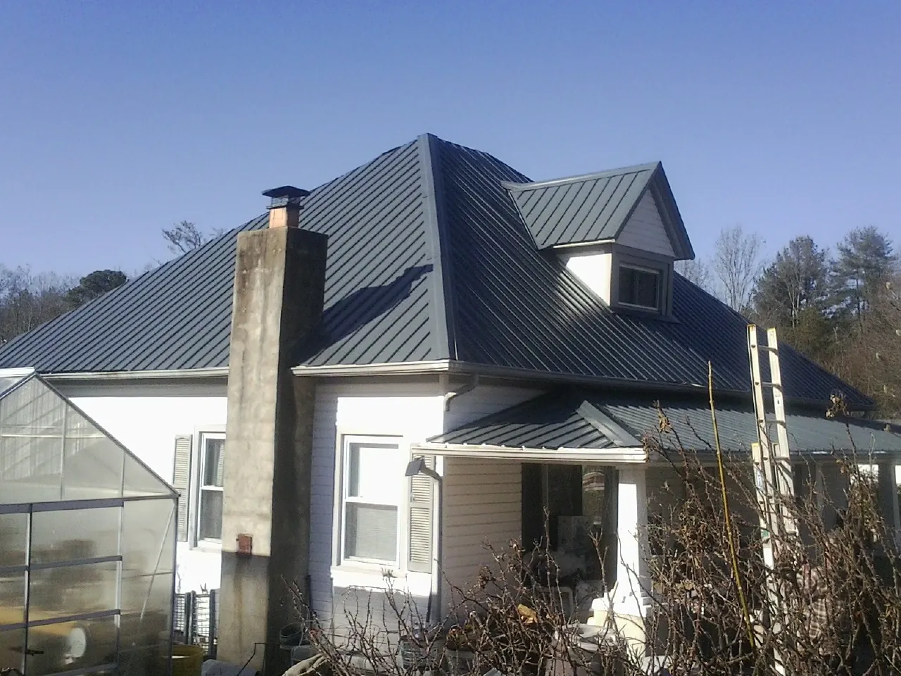 Dark blue standing seam metal roof on a white farmhouse with dormer — Slate & Tile Roof Repair by Roofing Brothers in Ravenna
