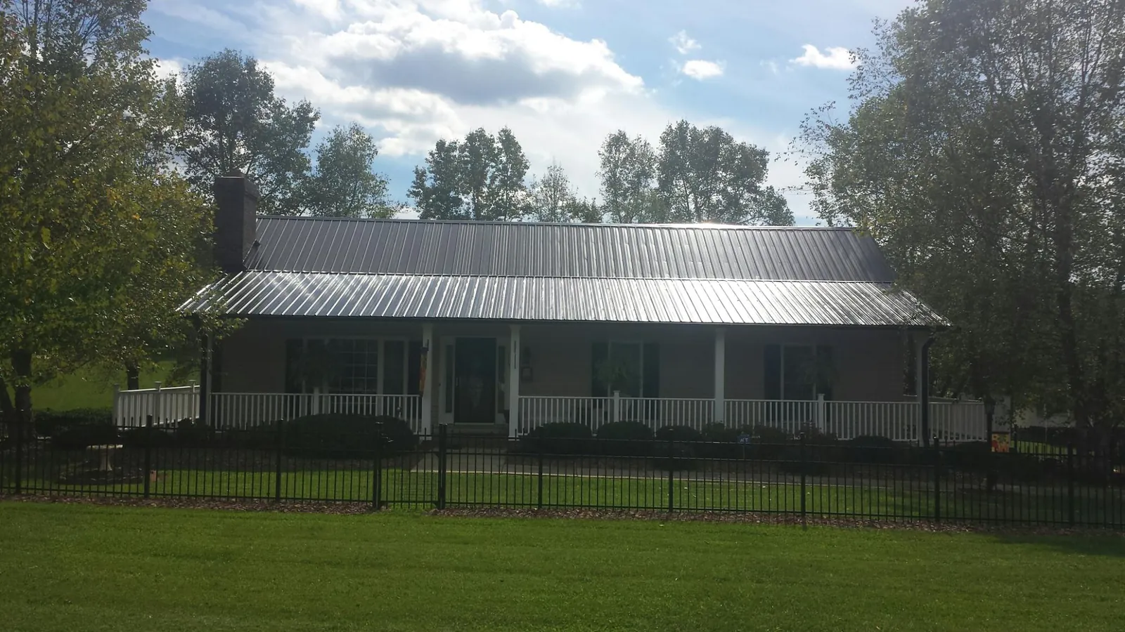 Gray metal roof on a brick ranch with a full width front porch — Gutter Guard Installation work by our crew in Ravenna