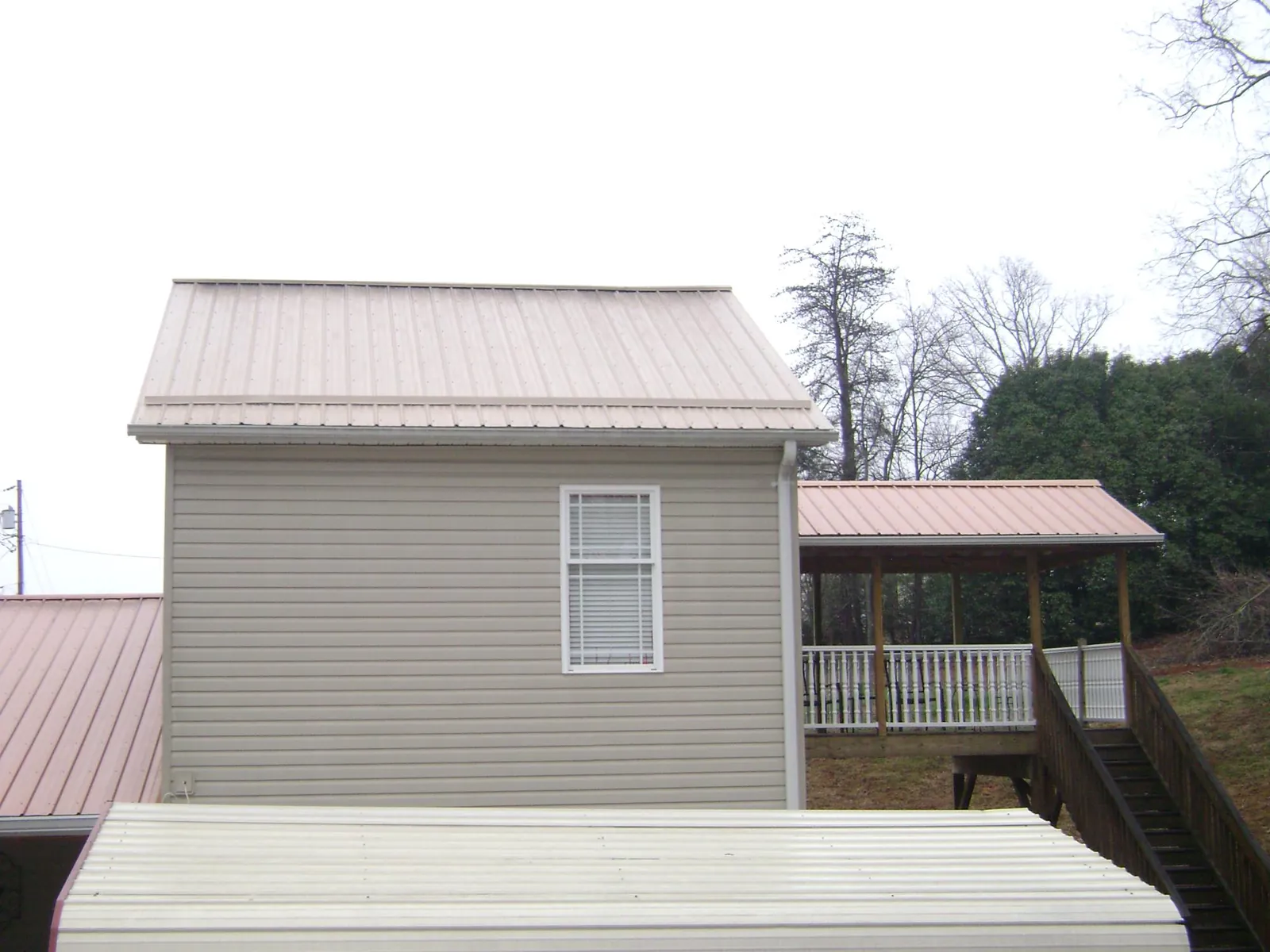 Tan metal roofs on a two story addition and attached porch, from a Roof Replacement job in Ravenna